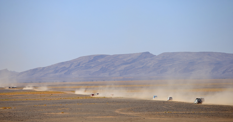 Convoi du 4L Trophy traversant le désert au pied des montagnes