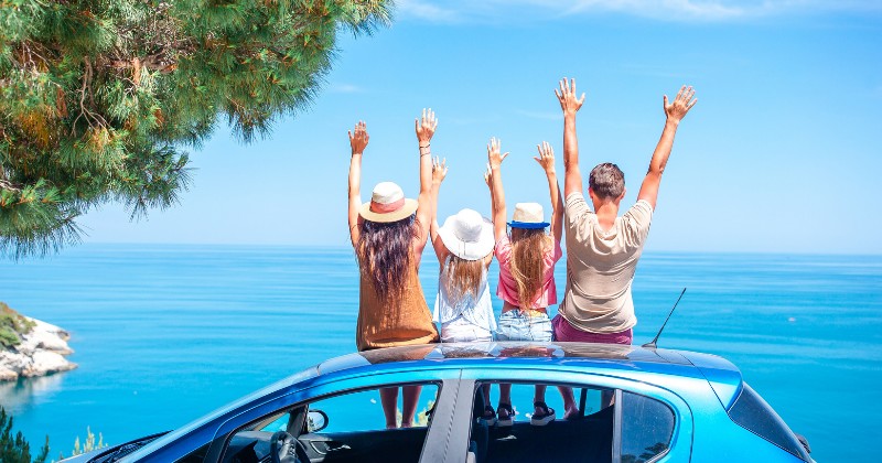 Famille assise sur une voiture, devant la mer